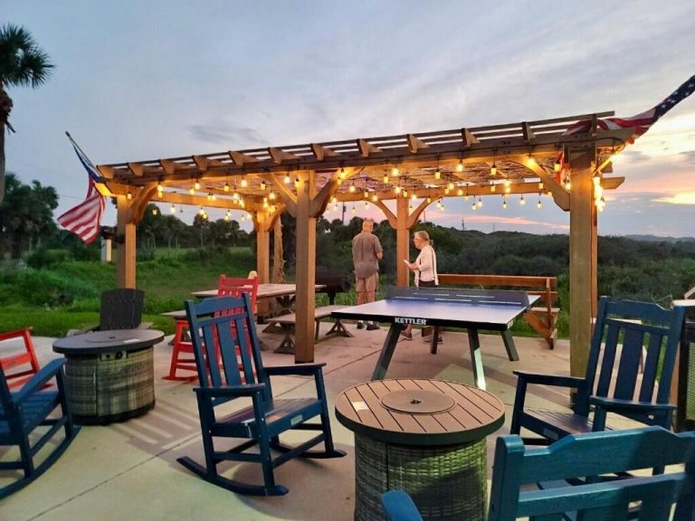 Terraza exterior con mesa de ping pong Kettler y pérgola iluminada al atardecer en Ocean Sands Beach Inn