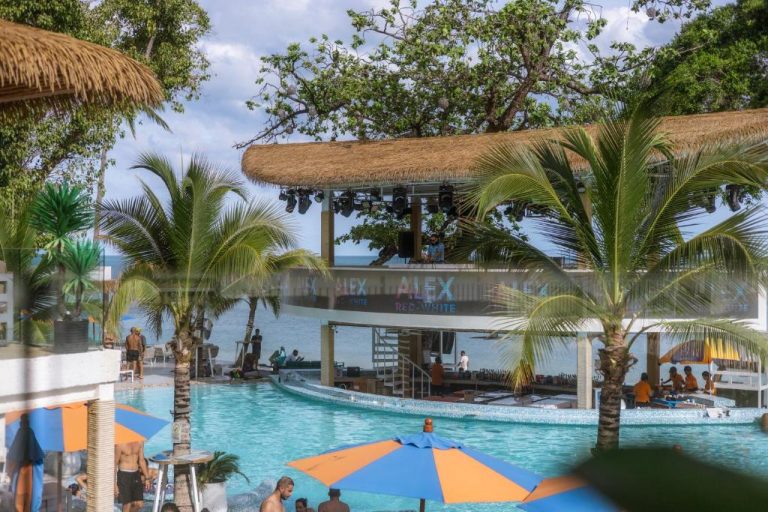 Piscina exterior con DJ booth y palmeras en ARKbar Beach Club & Resort con vistas al mar