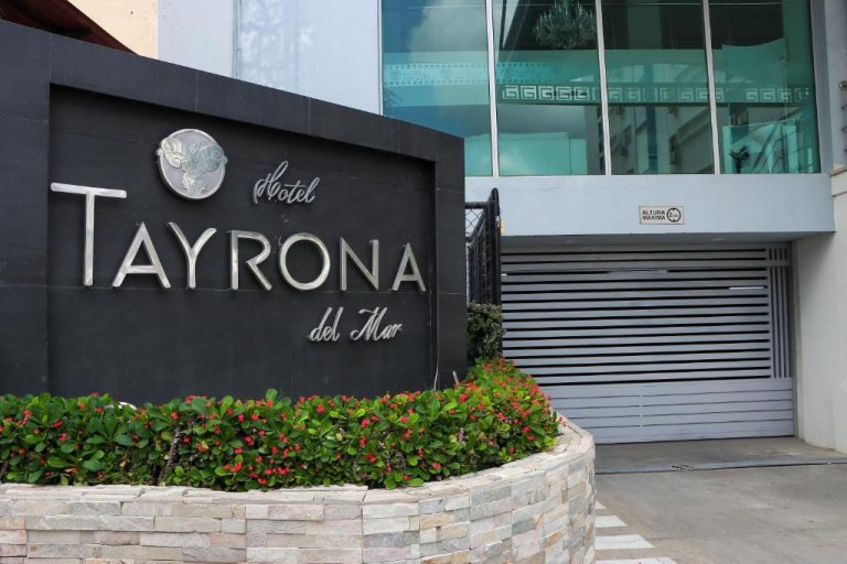 Fachada y entrada principal del Hotel Tayrona del Mar con jardín de flores rojas