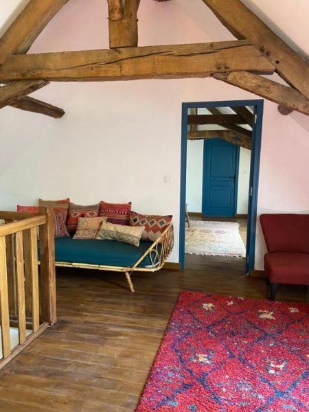 Salón rústico con vigas de madera y sofá con cojines del Moulin de Petoulle