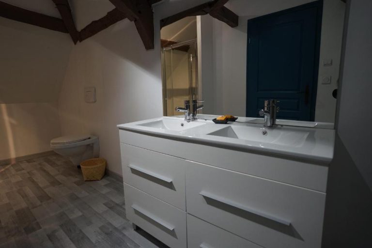 Baño moderno con doble lavabo blanco y espejo amplio en el Moulin de Petoulle