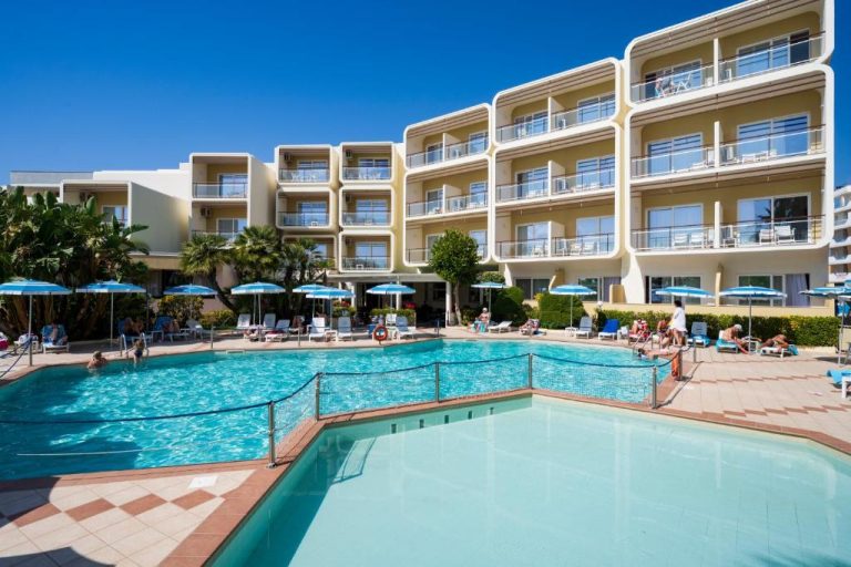 Piscina exterior con tumbonas y sombrillas azules del Hotel Florida en un día soleado