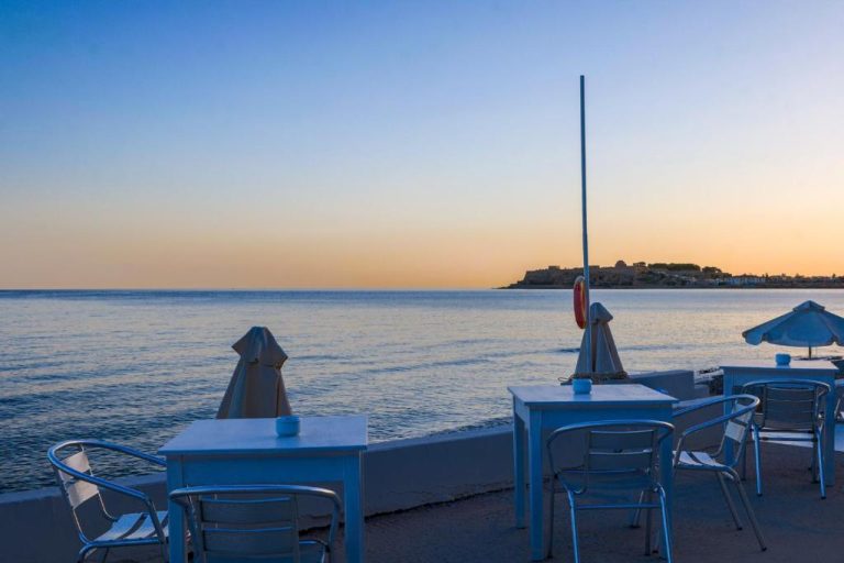 Terraza exterior del Filoxenia Beach con mesas y vistas al mar al atardecer