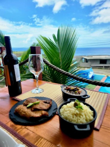 Plato de carne con arroz y vino tinto en la terraza con vista al mar del Fajã Beach House