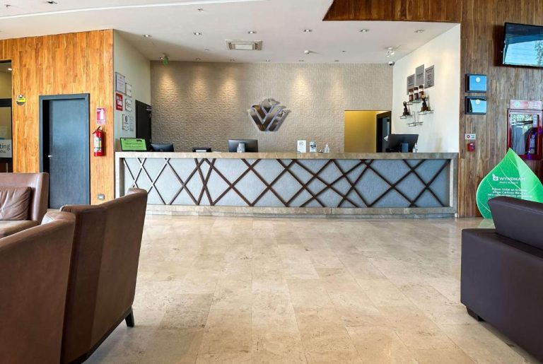 Recepción y lobby elegante del Hotel Wyndham Quito Airport con mostrador de mármol y diseño moderno