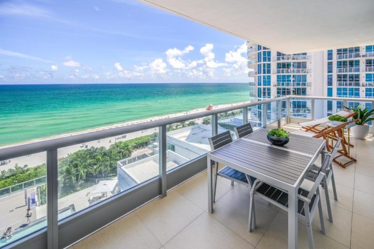 Terraza con mesa y sillas con vistas al mar turquesa y playa en Monte Carlo by Miami Vacations