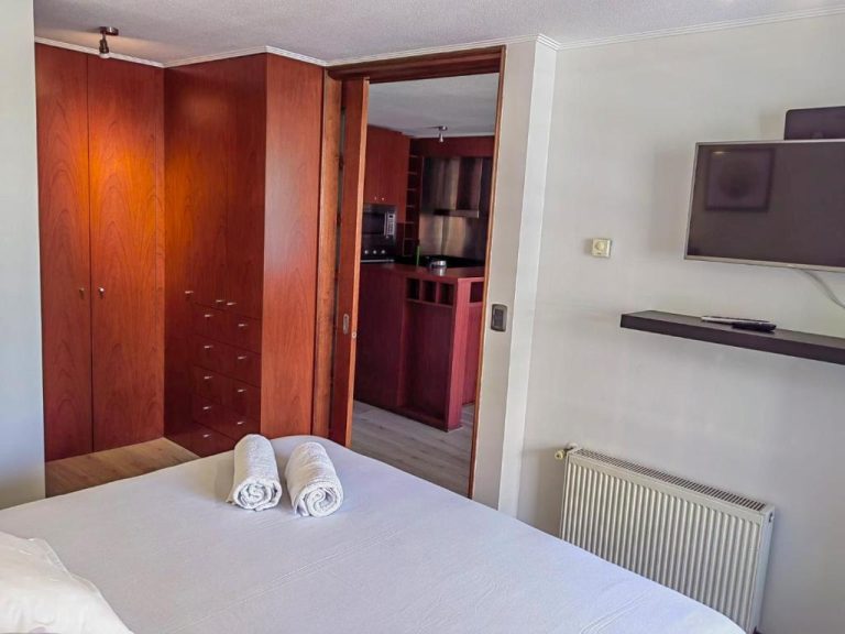 Habitación con armarios de madera, cama doble y cocina americana integrada en Apart Barrio El Golf
