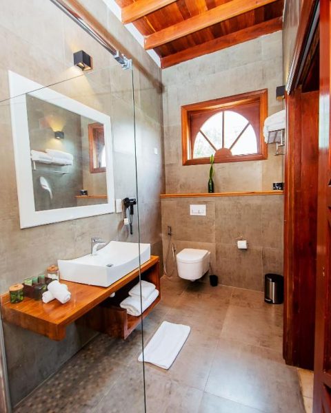 Baño moderno con ducha de cristal y lavabo sobre encimera de madera en The Seyyida Hotel and Spa