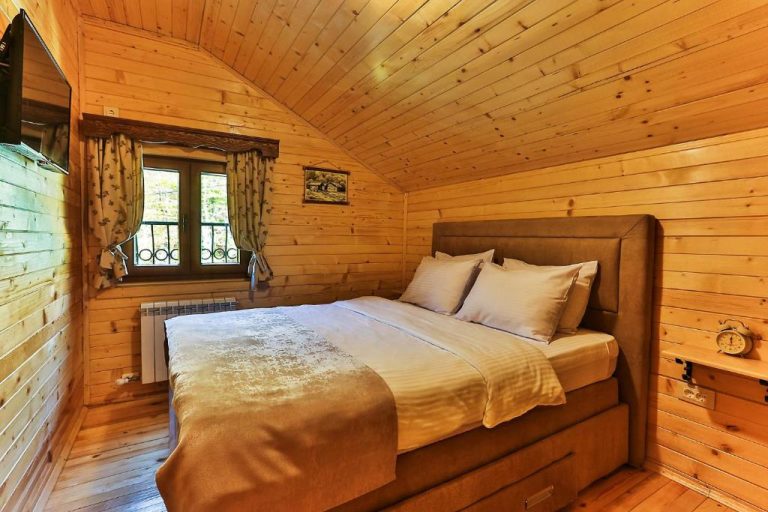 Habitación doble con techo abovedado de madera y cama matrimonial en Garni Hotel Elite Resort