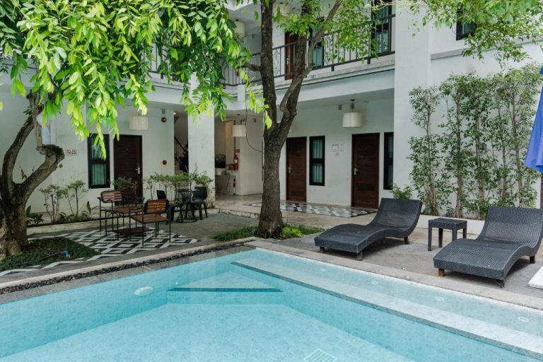 Piscina exterior con tumbonas y jardín interior del Paraiso Hotel Chiangmai rodeado de vegetación