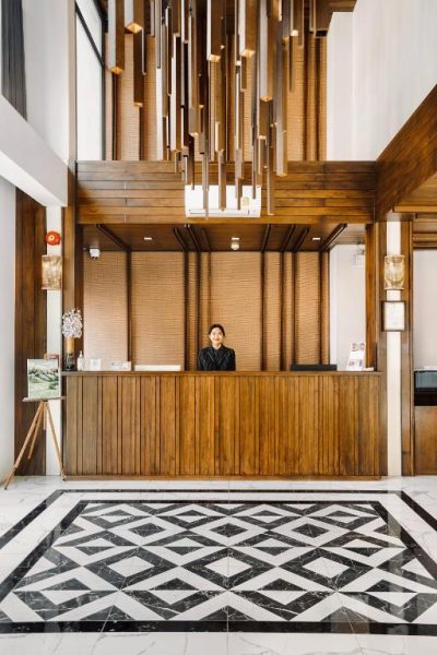 Recepción de madera con suelo de mármol en blanco y negro del Paraiso Hotel Chiangmai
