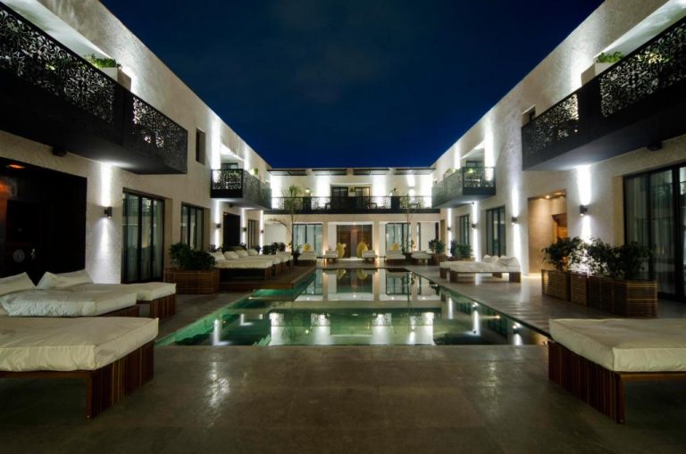 Piscina exterior iluminada de noche con tumbonas y terraza del Cesar Resort & Spa