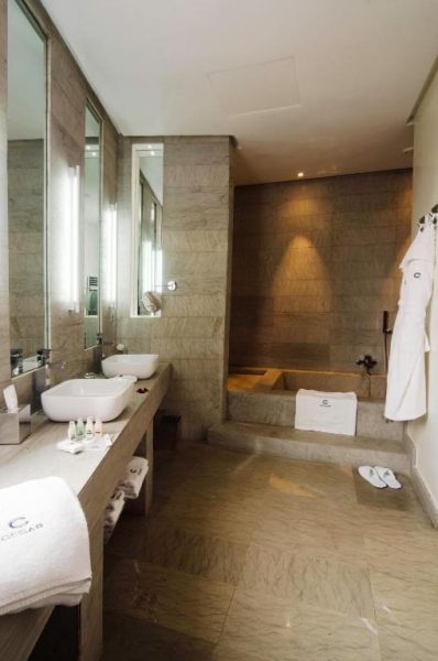 Baño de lujo con mármol, bañera empotrada y amenities en Cesar Resort & Spa