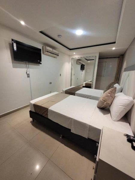 Habitación doble con dos camas y televisor en Hotel Med 33, aire acondicionado y espejo