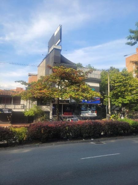Fachada exterior del Hotel Med 33 con vegetación tropical y cartelería comercial en primer plano