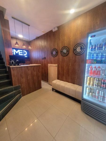 Recepción moderna del Hotel Med 33 con nevera de bebidas, paredes de madera y zona de espera