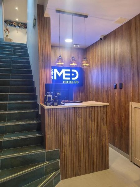 Recepción moderna con revestimiento de madera y letrero iluminado del Hotel Med 33