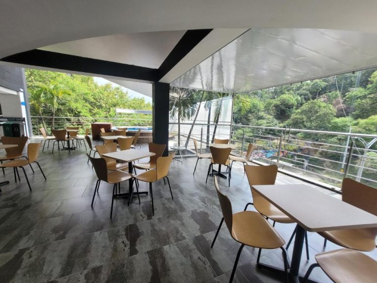 Terraza restaurante del Hotel Med 33 con mesas, sillas y vistas panorámicas al jardín y naturaleza
