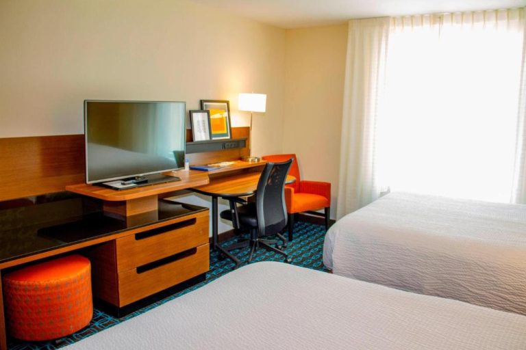 Habitación doble con dos camas, escritorio de trabajo y televisión en Wavecrest Lodge
