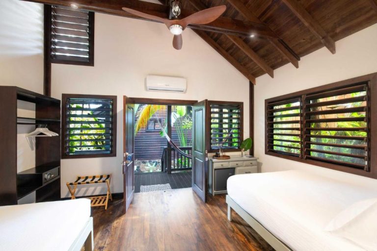 Habitación doble con techo de madera, ventilador y vistas a jardín tropical en Puerta Azul
