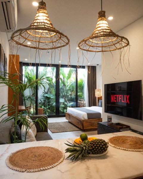 Salón con TV Netflix y decoración tropical en Sunny Aparts 2, con lámparas de ratán y frutas frescas