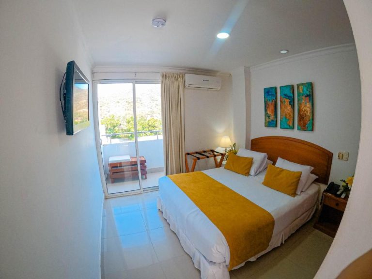 Habitación doble con cama matrimonial, balcón con vista a la montaña y TV en Hotel Tayrona Rodadero