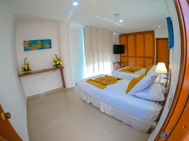 Habitación doble con camas blancas y decoración amarilla en Hotel Tayrona Rodadero Santa Marta