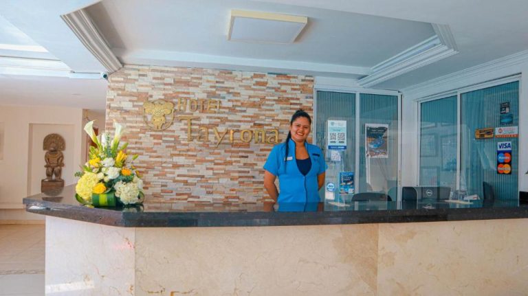 Recepcionista sonriente en el mostrador de bienvenida del Hotel Tayrona Rodadero con decoración floral