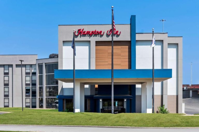 Fachada principal del Hampton Inn Indianapolis Northeast Castleton con entrada cubierta y banderas