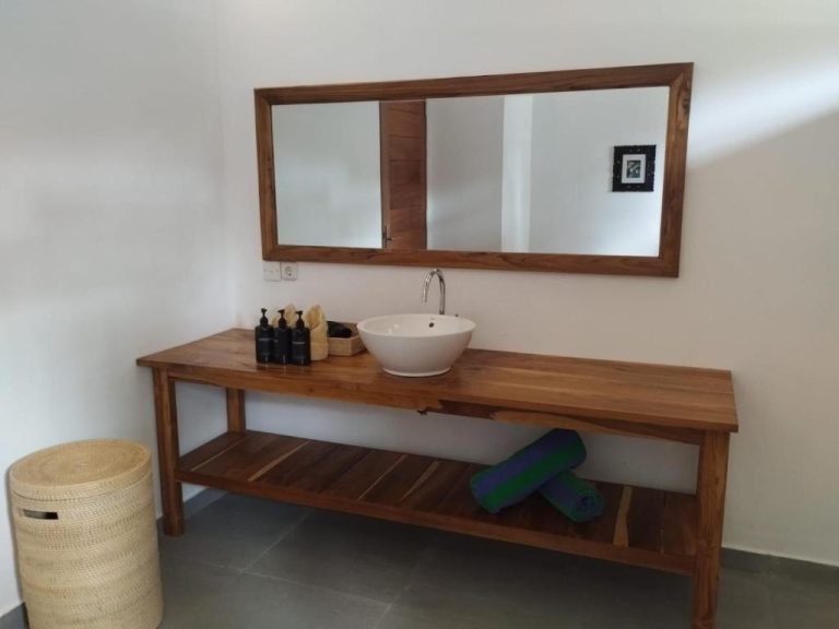 Baño con lavabo sobre encimera de madera y espejo en Villa Penyu Gili Trawangan