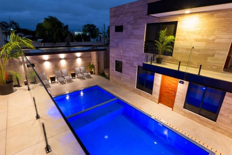 Piscina exterior iluminada de noche con área de descanso en Hotel 28 Cancún