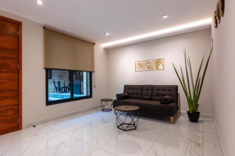 Sala de estar moderna con sofá oscuro y mesas auxiliares en Hotel 28 Cancun con vista a terraza