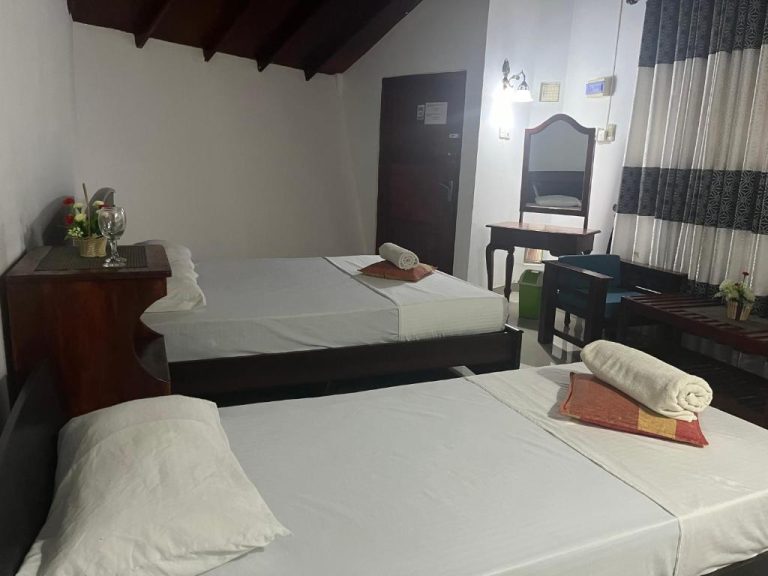 Habitación doble con dos camas y tocador con espejo en el Royal Green Garden de Puttalam