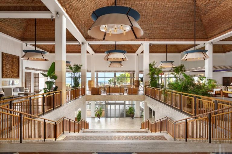 Amplio lobby con escalinatas, techos de madera y jardines interiores del Grande Real Santa Eulalia Resort & Spa