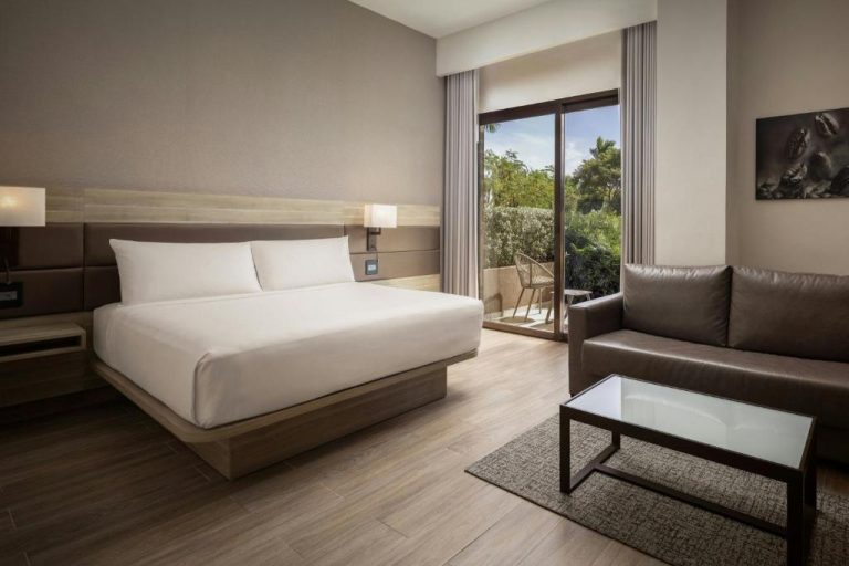 Habitación king con sofá de cuero y terraza con vistas al jardín en AC Hotel by Marriott Punta Cana