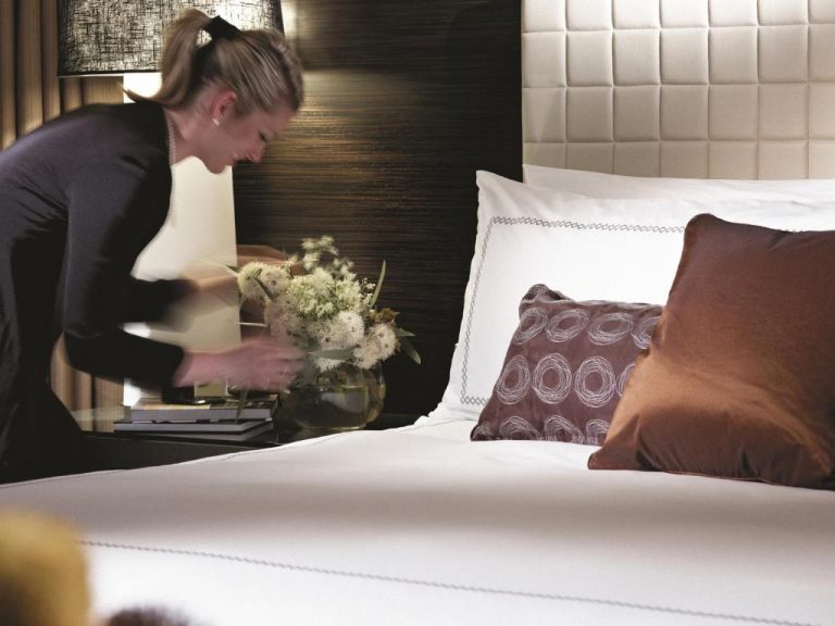 Camarera preparando la habitación de lujo con cama doble y flores en Four Seasons Hotel Sydney