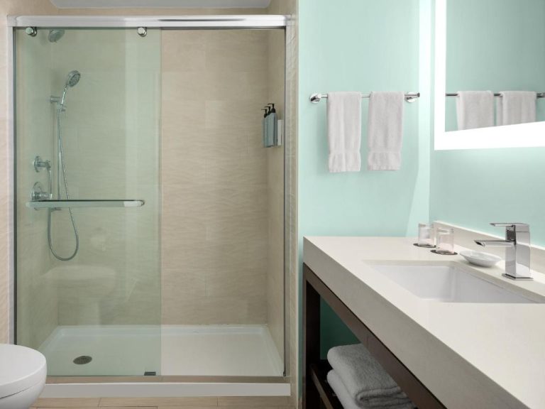 Baño moderno con ducha de cristal y lavabo del Courtyard by Marriott Nassau Downtown Junkanoo Beach