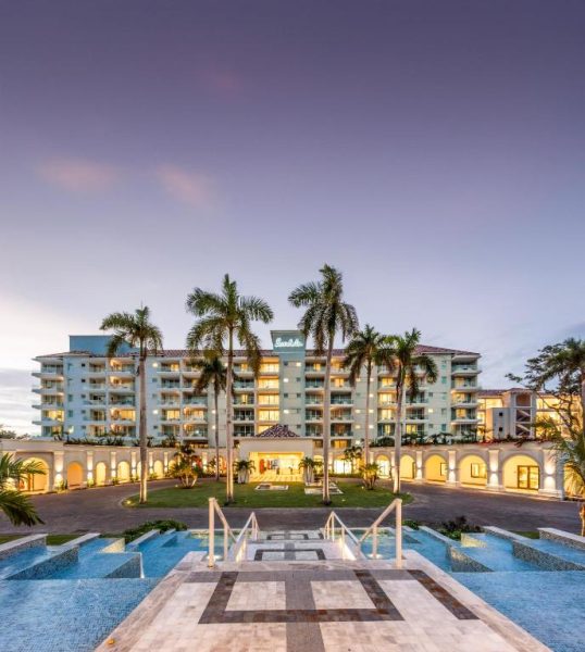 Fachada iluminada al atardecer del Sandals Dunns River con piscina y palmeras tropicales en Jamaica