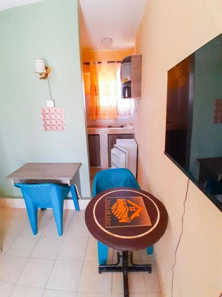 Salón comedor con mesa redonda, sillas azules y cocina equipada en Villa De Leo