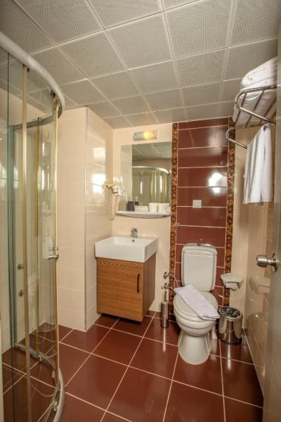 Baño completo con ducha de cristal, lavabo y aseo en el Perle Apart Hotel