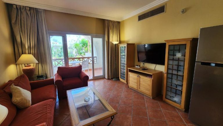 Salón con sofás rojos, televisión y terraza con jardín en Hotel Suite Jazz Sharm Dreams Vacation