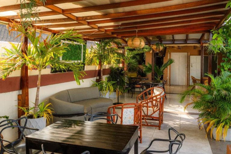 Terraza exterior con vegetación tropical, sofás y mesas del Hotel Marie Real Cartagena
