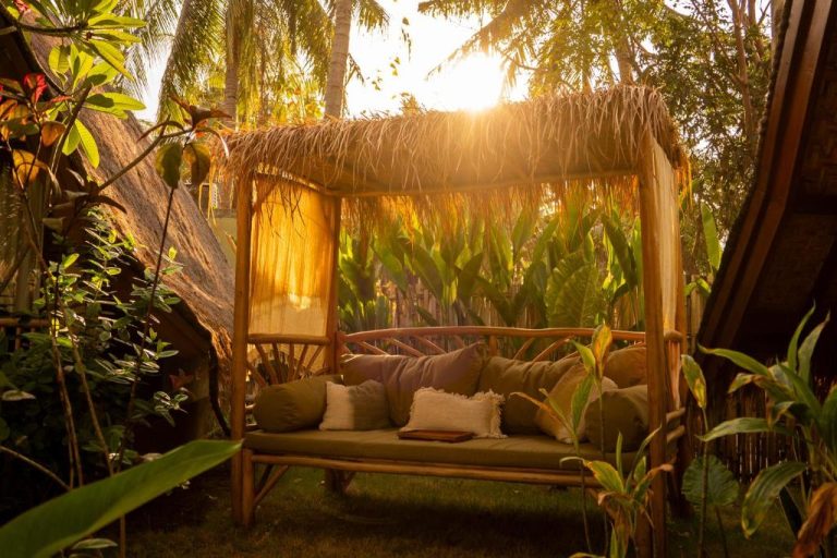 Cama de bambú con dosel de paja rodeada de vegetación tropical al atardecer en Hotel Selvática