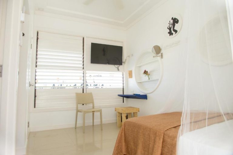 Habitación blanca con tocador, espejo oval y TV del Begona Cliff Hotel