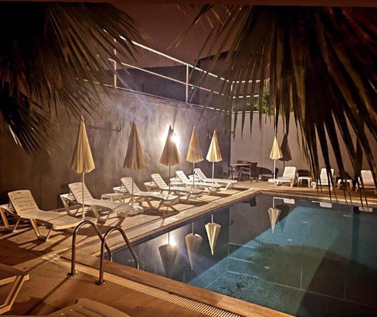 Piscina exterior iluminada de noche con tumbonas y sombrillas en Hotel Alanya Afd