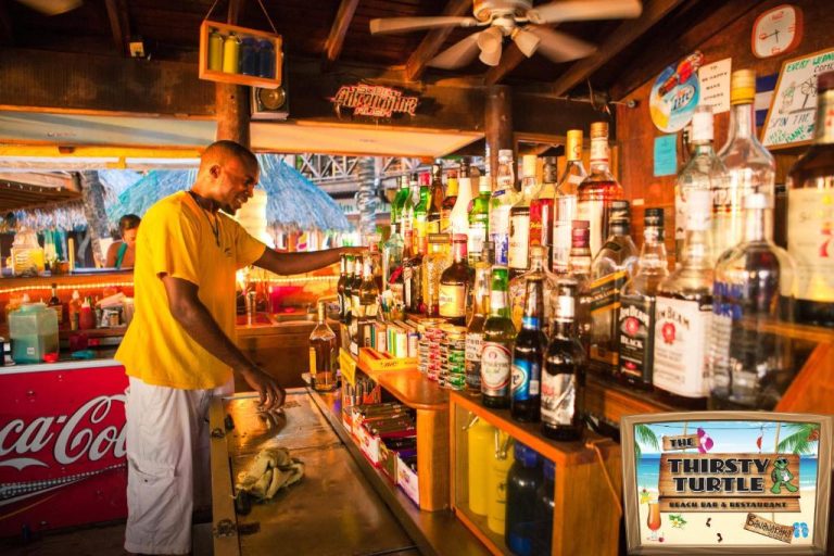 Bartender preparando bebidas en el bar de playa Thirsty Turtle del Bananarama Dive & Beach Resort