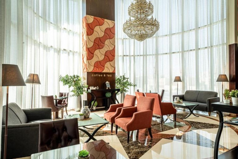 Elegante lobby con zona de café y té del Kingsgate Hotel Doha by Millennium Hotels con gran lámpara de cristal