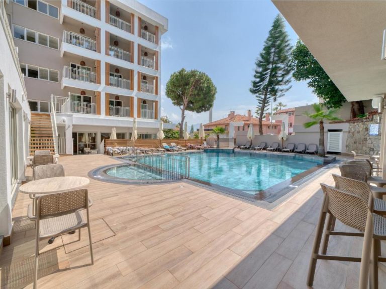 Piscina exterior con terraza y tumbonas del Park Hotel rodeada de edificio con balcones