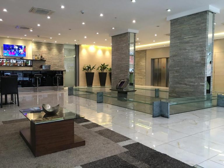 Lobby moderno del Crystal Tower con columnas de piedra, bar y decoración elegante en mármol