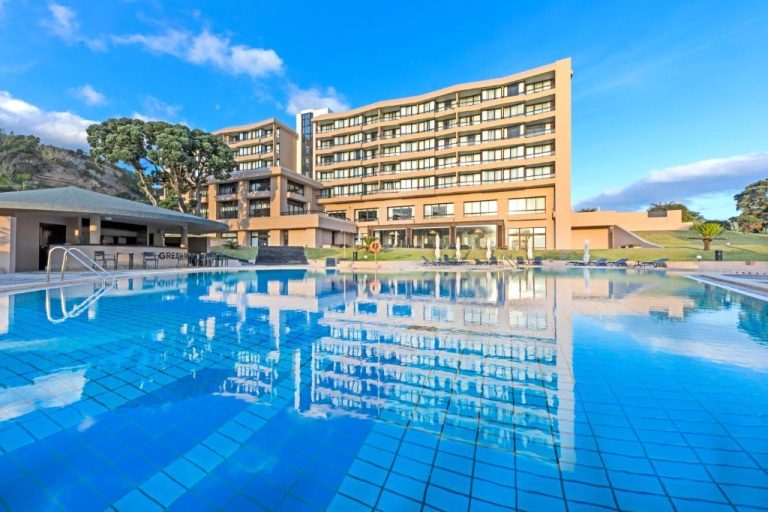 Amplia piscina exterior con reflejo del edificio principal del Pestana Bahia Praia Nature & Beach Resort